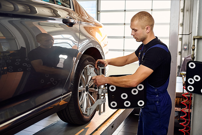 Аuto mechanic sets the car for diagnostics and configuration collapse-convergence. Car Wheels alignment equipment on stand in a repair station.