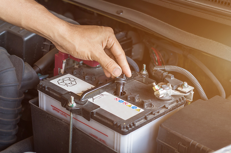 Auto mechanic working check system water and battery fill an old