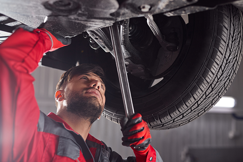 Mechanic fixing car chassis in workshop